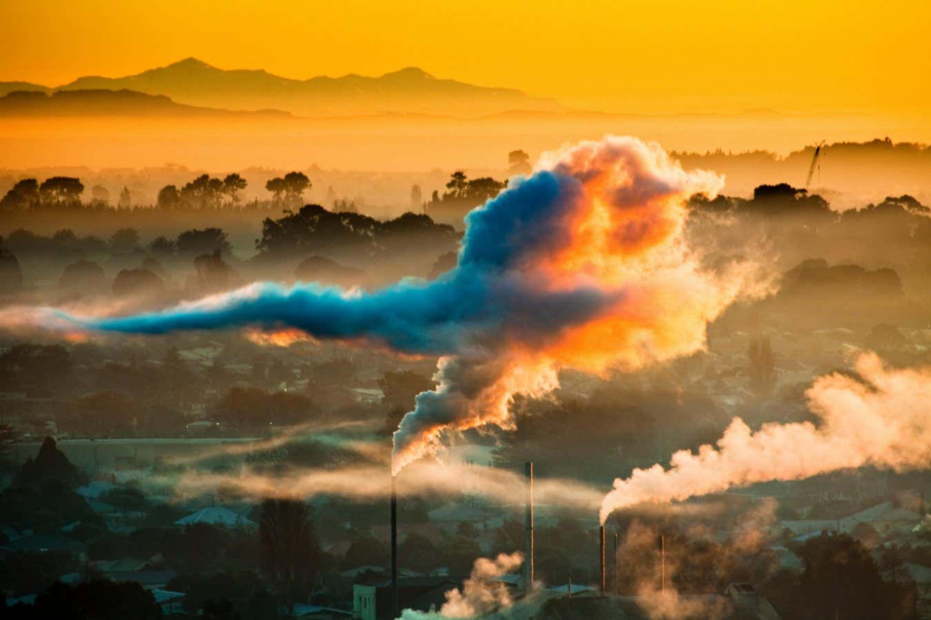 H7XCR8 Winter dawn over industrial chimneys with Seaward Kaikoura Range behind, Christchurch, New Zealand